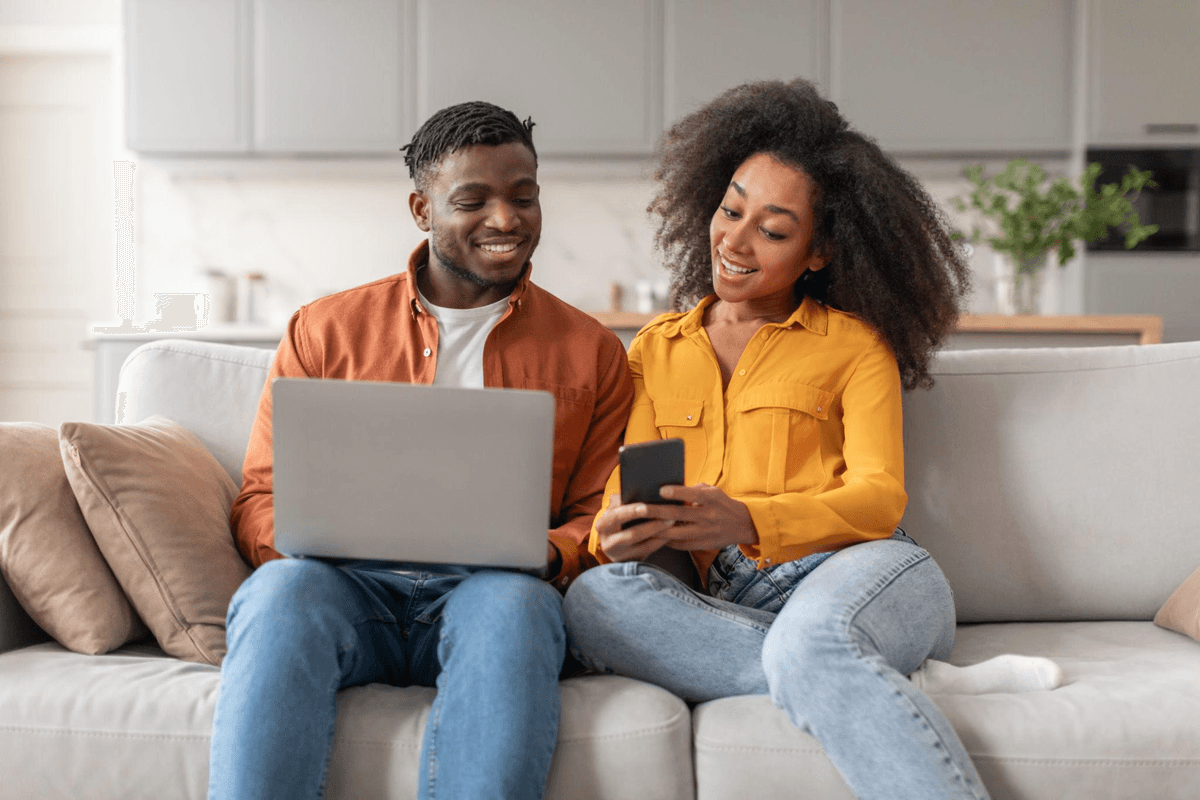 Couple on the couch checking a phone and laptop together